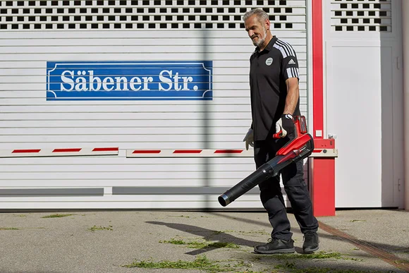 Person bläst Laub mit einem Laubbläser.